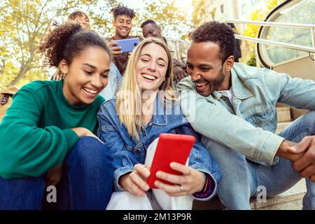 Young group of international friends watching social media content on phone app Stock Photo