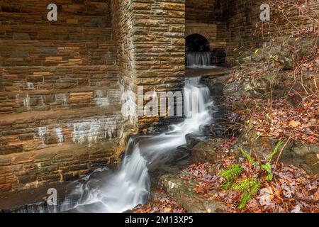 A small initial spillway on Byrd Creek Dam in Cumberland Mountain Tennessee shows the fall colors and brick details as the water flows down to the riv Stock Photo