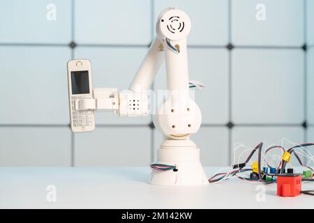 Robotic arm holding mobile phone Stock Photo
