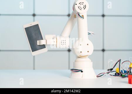 Robotic arm holding mobile phone Stock Photo