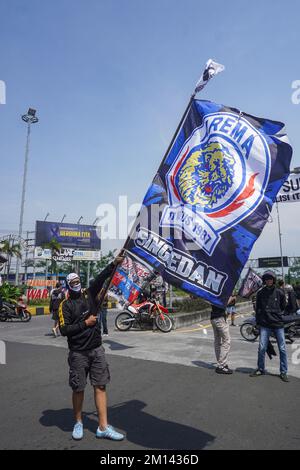 A demonstrator carries a flag with the Crazy Lion logo of the soccer team Arema FC, during the protest. Aremania, the supporters of Arema FC, held a rally and blocked streets in some spots in Malang to protest the legal process of the soccer stampede tragedy, which killed 135 people due to the police tear gas at Kanjuruhan Stadium on October 1, 2022. Stock Photo