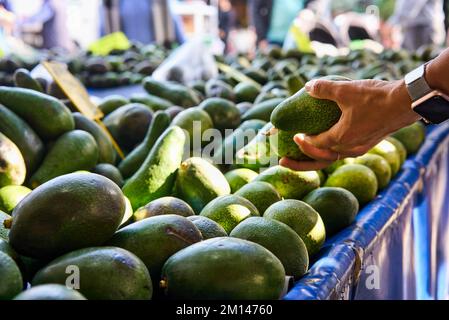 Young Woman Choosing Avocados in Grocery market. Concept of healthy food, bio, vegetarian, diet. High quality photo Stock Photo