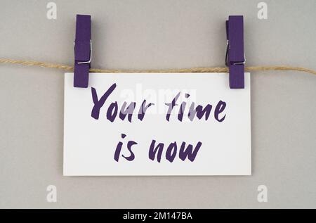 Business and people concept. On a gray background, a business card with the inscription - Your time is now Stock Photo