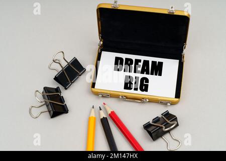 Business concept. On the table are pencils, paper clips and a business card holder, inside which is a business card with the inscription - DREAM BIG Stock Photo