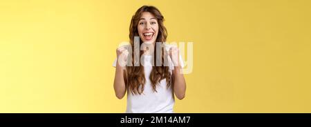 Yes finally success. Cheerful enthusiastic happy girl pump fists lift hands victory joy celebration gesture smiling broadly relieved winning lottery Stock Photo