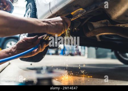 Blue-collar worker concept. Angle grinder in use. Dangerous heat sparkles. Two hands of caucasian mechanic. Indoor low angle view. High quality photo Stock Photo