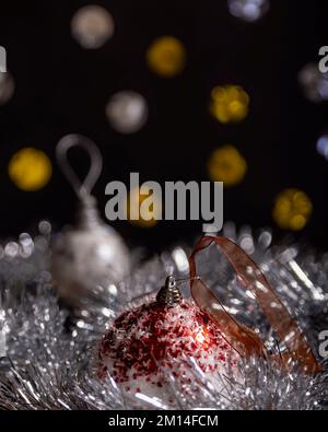 Close up view of a Christmas ball with a red bow and blurry fairy lights in the background Stock Photo