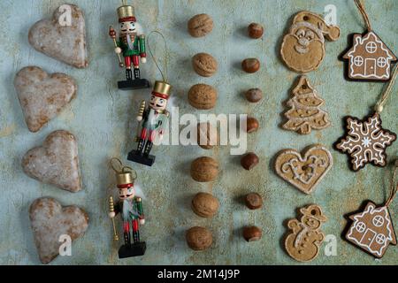 Gingerbread cookies with icing or frosting, Christmas nutcracker wooden figures, walnuts, hazelnuts and tree pendant decorations ornaments. Stock Photo