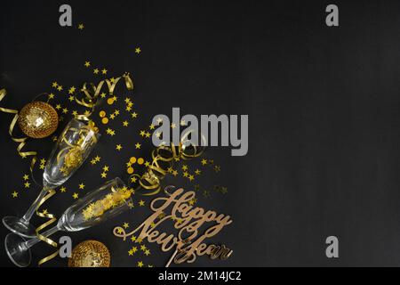 Champagne glasses, golden decorations, confetti, streamers for New Year's Eve party celebration. Happy New Year flat lay composition with copy space. Stock Photo
