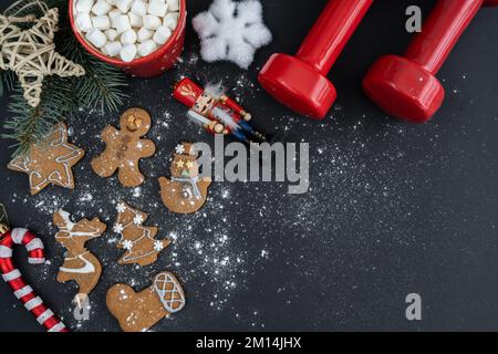 Homemade gingerbread Christmas cookies, gym dumbbells, hot chocolate cocoa with marshmallows. Fitness winter workout diet, flat lay with copy space. Stock Photo