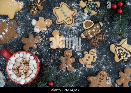 Homemade gingerbread Christmas cookies with icing or frosting, covered in flour. Hot chocolate cocoa with marshmallows. Flat lay composition. Stock Photo