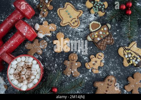 Homemade gingerbread Christmas cookies, dumbbells, hot chocolate cocoa with marshmallows. Fitness winter diet, gym workout, dieting flat lay concept. Stock Photo