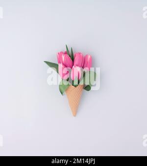 An ice cream cone with pretty pink tulip flowers on the white background Stock Photo