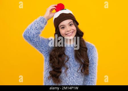 Modern teenage girl 12, 13, 14 year old wearing sweater and knitted hat on isolated yellow background. Happy teenager, positive and smiling emotions Stock Photo