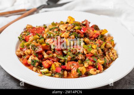 Gavurdagi salad on dark background. Turkish cuisine appetizer flavors. Salad made with walnuts, tomatoes, green peppers, onions, parsley and cucumbers Stock Photo
