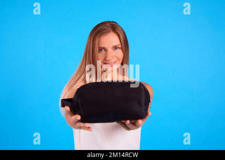 focus on woman face on background. daily skin care in small cosmetic bag. woman wrapped in white towel on blue background Stock Photo
