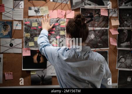 Private detective looking attentively at investigation board, back view. Copy space Stock Photo