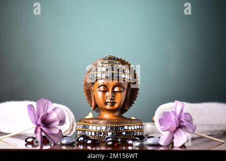 Handcrafted buddha face on table with flowers Stock Photo