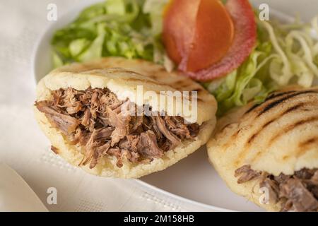 Close up of Arepas, typical Venezuelan food, made with maize and filled with shredded meat. Stock Photo