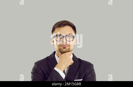Serious businessman with doubtful uncertain facial expression hesitates to make important decision. Stock Photo