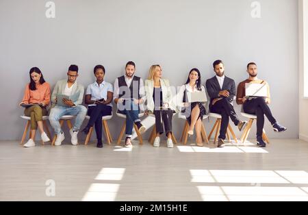 Group of different multiethnic people sitting in row in waiting room before interview or meeting. Stock Photo
