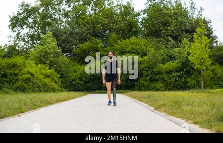 Man athlete with leg prosthesis walking in the park - Hispanic man enjoying a training outdoor Stock Photo