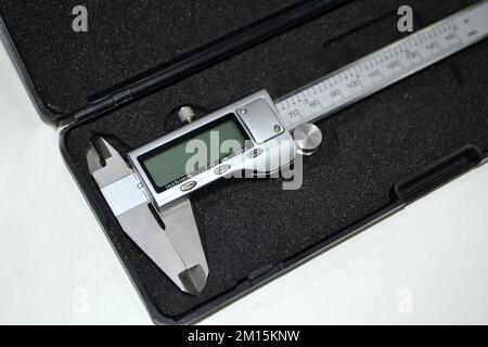 Digital electronic vernier caliper in plastic black box isolated on white background closeup. Engineering industrial measuring equipment. Universal high-precision measuring device instrument. Stock Photo
