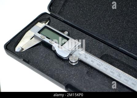 Digital electronic vernier caliper in plastic black box isolated on white background closeup. Engineering industrial measuring equipment. Universal high-precision measuring device instrument. Stock Photo