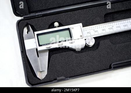 Digital electronic vernier caliper in plastic black box isolated on white background closeup. Engineering industrial measuring equipment. Universal high-precision measuring device instrument. Stock Photo