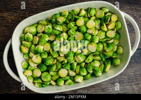 Overhead View of Halved Brussels Sprouts Tossed in Extra Virgin Olive Oil: A baking dish full of raw Brussels sprouts cut in half and tossed in olive Stock Photo