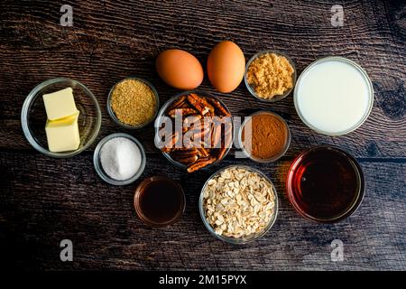 Pecan Pie Baked Oatmeal Ingredients Flat Lay on a Wood Table: Rolled oats, pecan halves, and other ingredients for a healthy breakfast dish Stock Photo