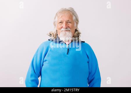 Delightful senior male with gray hair and beard looking at camera while standing on white background Stock Photo