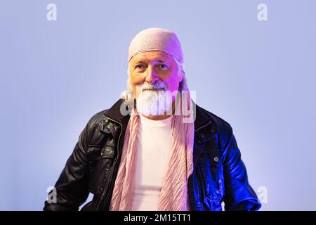 Confident bearded senior man in leather jacket and bandana looking at camera against white background Stock Photo