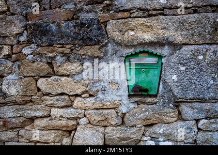 Green colored metal vintage mail box in wall made of rough aged stones in old house Stock Photo