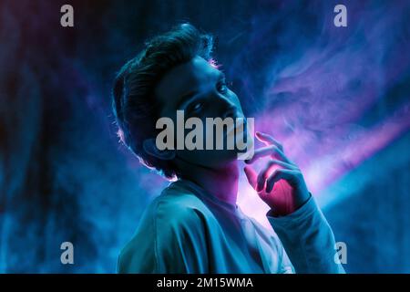 Young handsome man in dark t shirt standing looking at camera on purple background Stock Photo