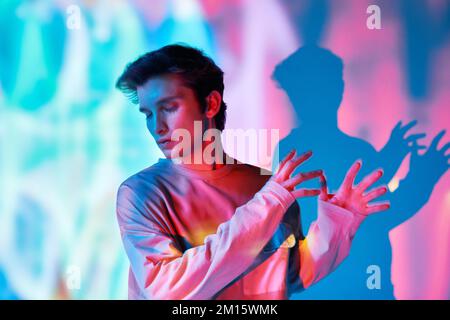 Artistic creative portrait of man with eyes closed in multicolored neon lights colorful background Stock Photo