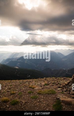 Scenic view of sun rays shining through clouds on mountain ridge covered with grass Stock Photo