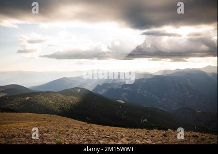 Scenic view of sun rays shining through clouds on mountain ridge covered with grass Stock Photo