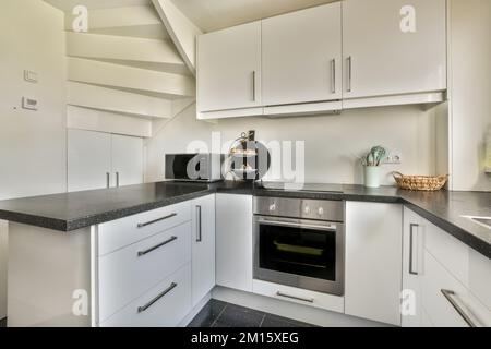 Counters with appliances located against wall with built in furniture in light kitchen at home Stock Photo