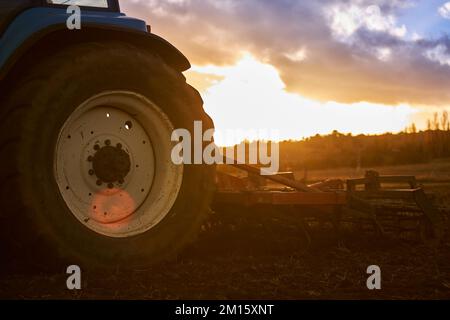 View of tractors wheel during work on field against cloudy sundown sky in countryside Stock Photo