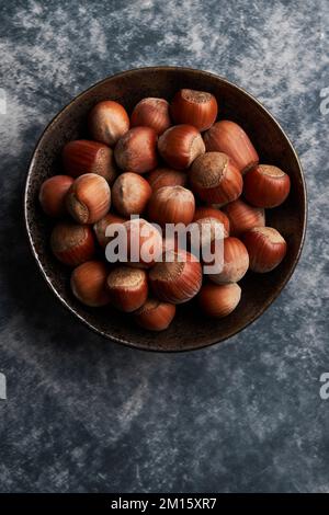 From above bunch of ripe hazelnuts in bowl on marble table Stock Photo