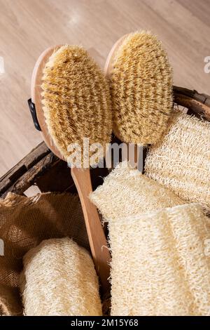 Top view of wooden basket placed on floor filled with brushes and zero waste natural luffa sponges Stock Photo