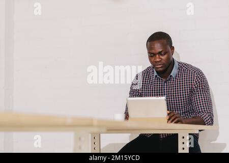 Black Man with a Digital Tablet on a Wooden Table Stock Photo
