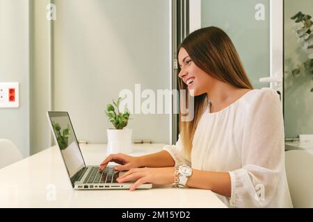 Young Happy Businesswoman Working with a Laptop and looking at screen Stock Photo