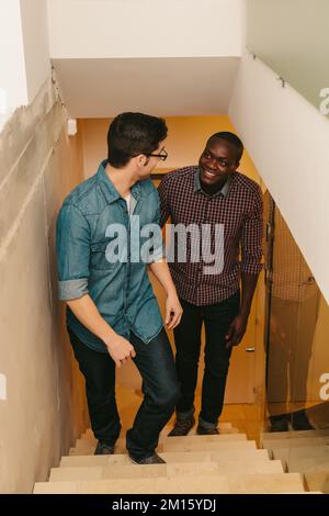 Two men climbing up the ladder in a modern office Stock Photo