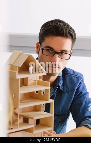 Young architect working on a wooden model at office Stock Photo