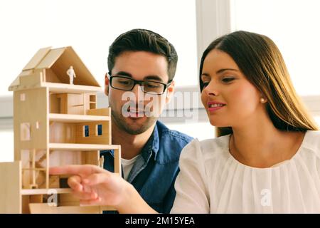 Two young architects working on a wooden model at office Stock Photo