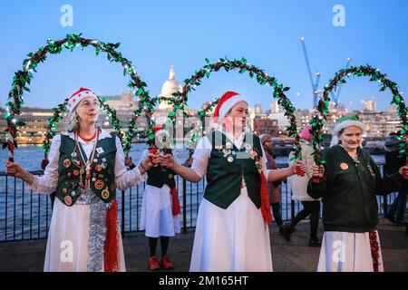 London, UK. 10th Dec, 2022. A group with illuminated garlands dances in the annual festive Morris Dancers Ale, a get together of about 50 dancers in several different groups who walk along the South Bank and dance outside the Founders Arms near Tate Modern. The walk and dance are organised by North Wood Morris Dancers. Credit: Imageplotter/Alamy Live News Stock Photo