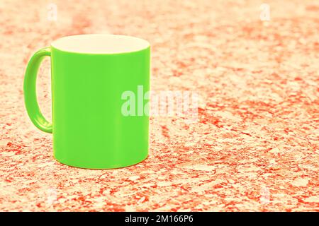 Green ceramic cup mug on orange yellow spotted background Stock Photo