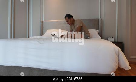 Man working with laptop on bed while working from home Stock Photo